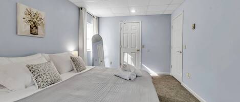 A bedroom with a large bed, a white door, and a painting on the wall.