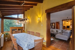 A dining area with a table set for six, surrounded by wicker chairs, a wooden ceiling, and a view of the outdoors.