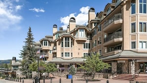 Un hotel de varios pisos con fachada de piedra, ventanas grandes y balcones.