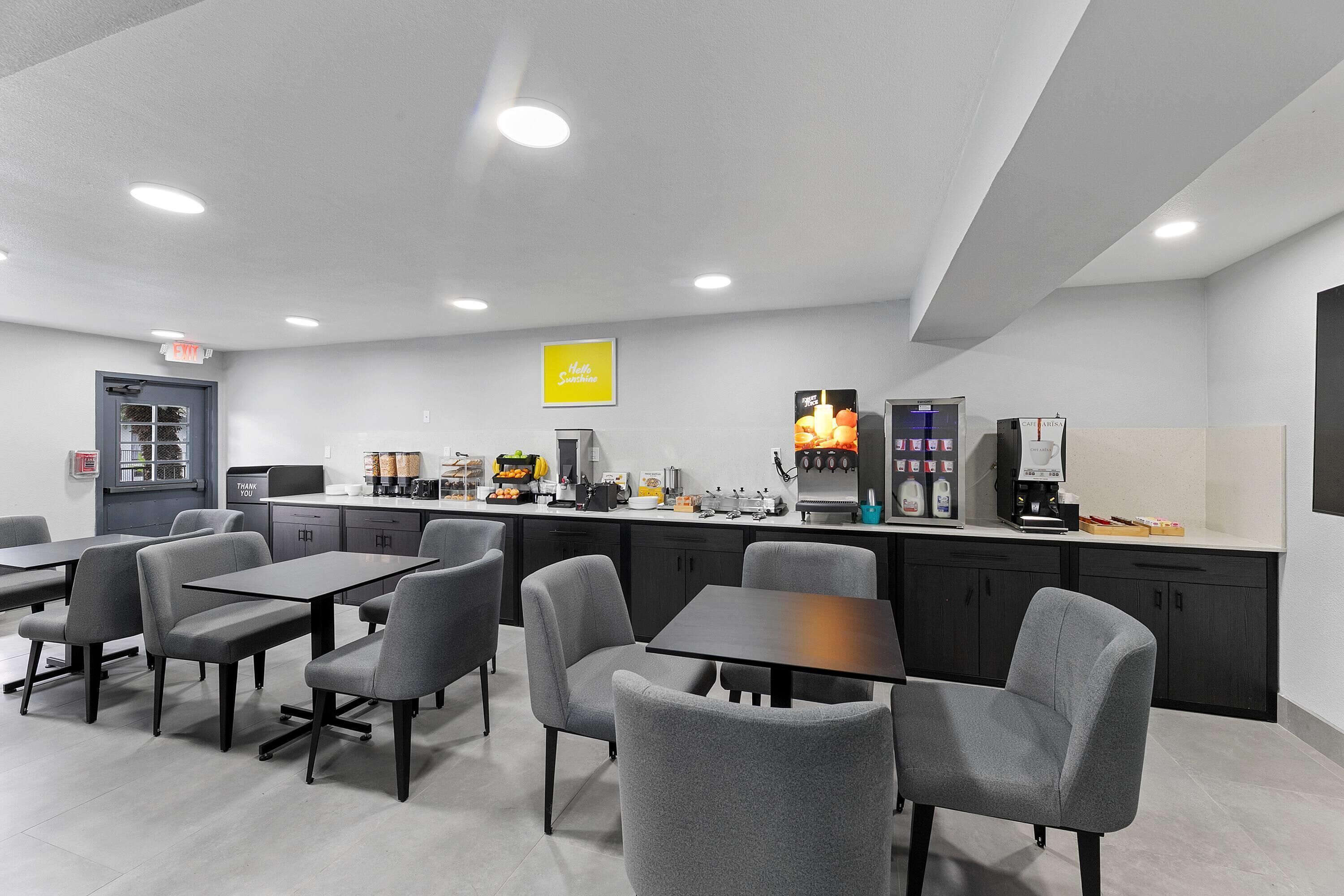 A modern kitchen with grey chairs, a coffee station, and a sign that says "Thank You".