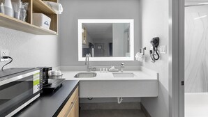 A modern bathroom with a double sink, a large mirror, and a hairdryer mounted on the wall. - Days Inn By Wyndham San Antonio Near Lackland Afb (San Antonio)