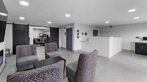 A modern hotel lobby with seating areas, a reception desk, and a kitchen area. - Days Inn By Wyndham San Antonio Near Lackland Afb (San Antonio)