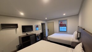 A hotel room with two beds, a TV, a desk, and a window with a view of the Golden Gate Bridge. - Travelodge By Wyndham Bainbridge (Bainbridge)