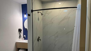 A modern bathroom with a glass-enclosed shower, a vanity with a mirror, and a towel rack. - Travelodge By Wyndham Bainbridge (Bainbridge)