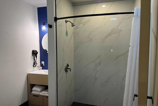 Un baño moderno con cabina de ducha de vidrio, tocador con espejo y perchero.