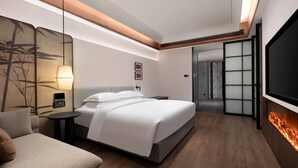 Une chambre d’hôtel moderne avec un grand lit, un canapé, une télévision et une cheminée.
