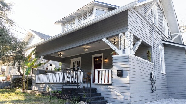 A two-story house with a covered porch, a front door, and a small staircase leading to the entrance.
