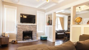 A living room with a brick fireplace, a television mounted above it, and a sofa.