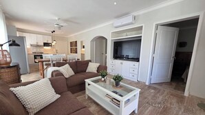 A modern living room with a brown sofa, a glass coffee table, and a TV in the background. - Villa Mare B3 (on the beach Bavaro) Los Corales (Punta Cana)