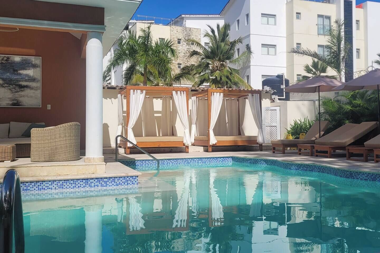 Ett poolområde med en paviljong, solstolar och utsikt över hotellbyggnaderna.