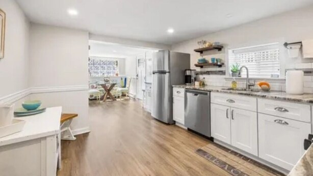 A modern kitchen with white cabinets, stainless steel appliances, and a wooden floor. - Charming 2-bedroom apartment with AC, WiFi in peaceful Ventnor City (Ventnor City)