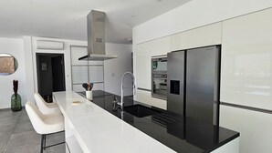 A modern kitchen with white cabinetry, a black countertop, and stainless steel appliances including a refrigerator and oven. - Villa Haut Standing Stella Di Mare panoramic view (Propriano)
