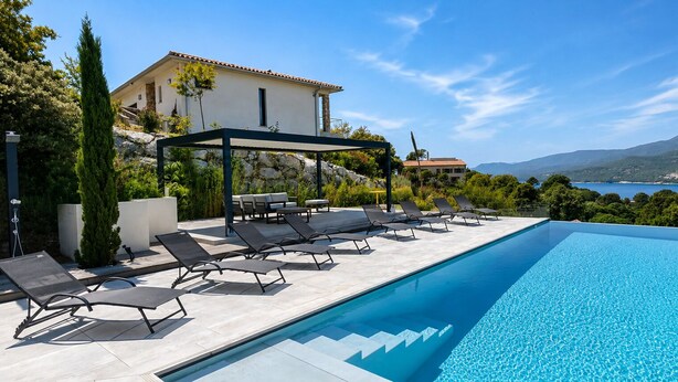 A swimming pool with lounge chairs, a covered seating area, and a view of the sea and mountains. - Villa Haut Standing Stella Di Mare panoramic view (Propriano)