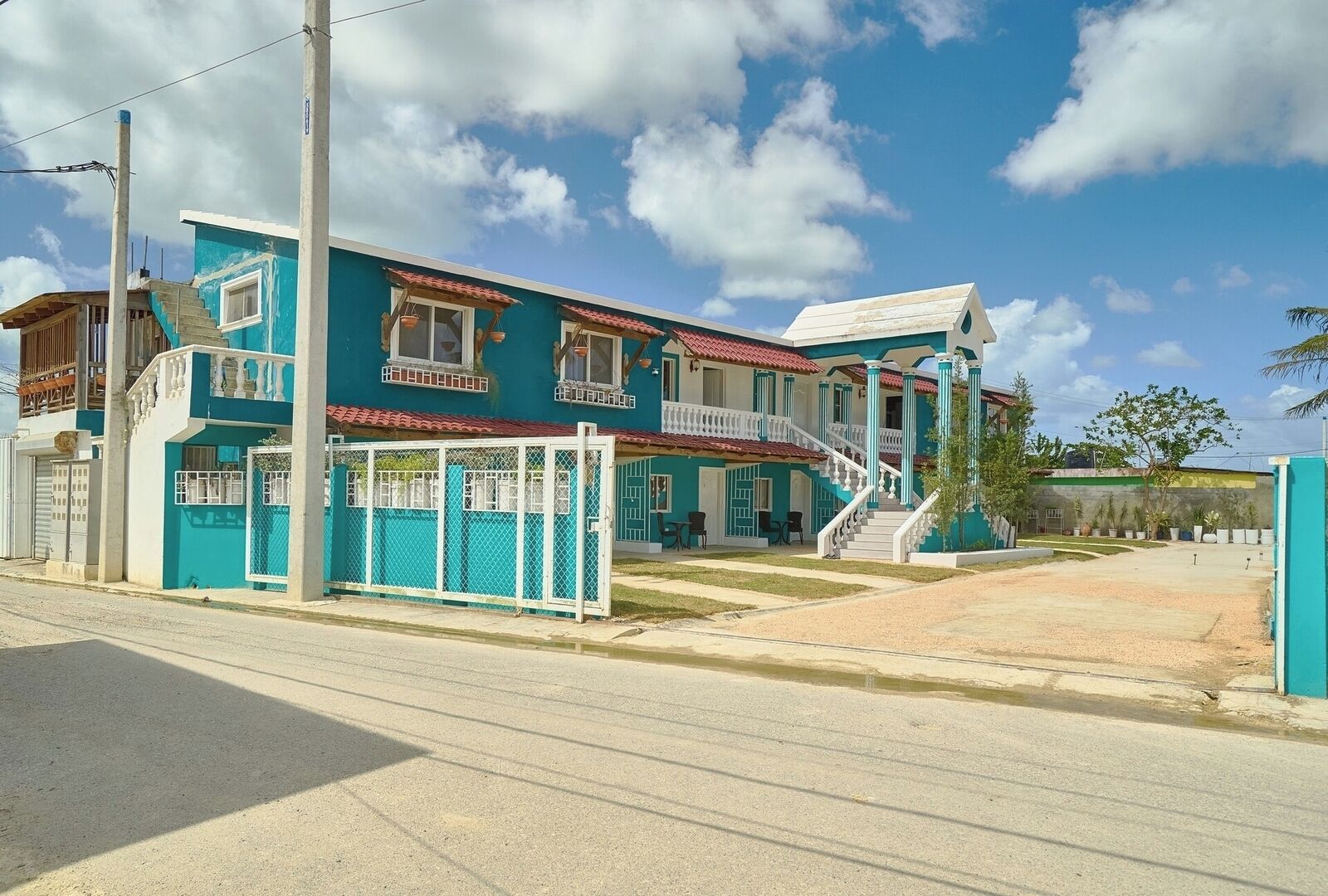 A two-story building with a blue facade, a white balcony, and a red-tiled roof.