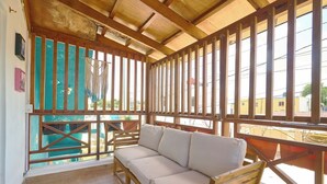 A wooden balcony with a beige sofa, wooden railings, and a view of the outside. - The Patio Hotel #8 15 minutes from Macao Beach (Punta Cana)