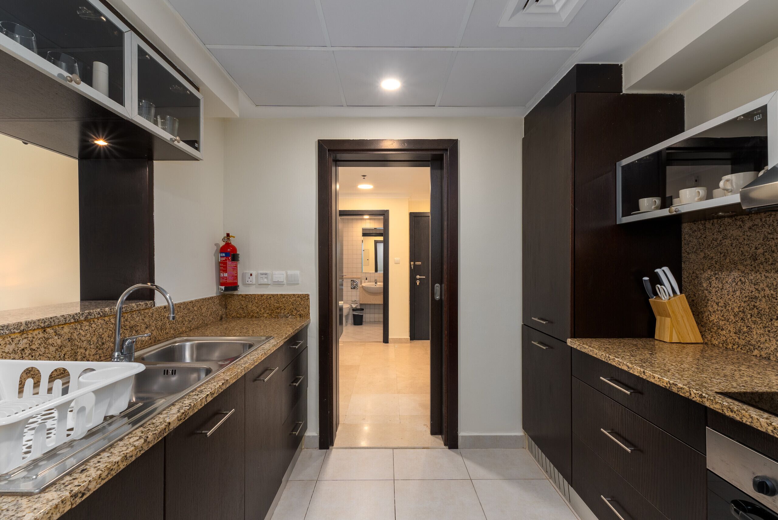 Una cocina moderna con encimeras de granito, electrodomésticos de acero inoxidable y muebles oscuros.