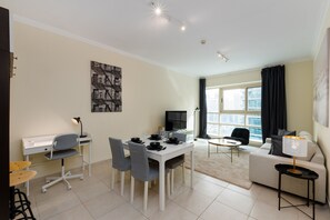 A modern living room with a dining area, a sofa, a TV, and a large window with curtains.