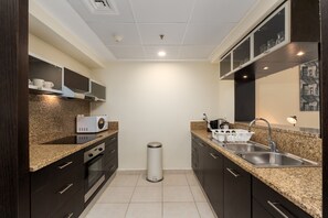 A modern kitchen with dark cabinetry, granite countertops, a stainless steel sink, and a microwave.