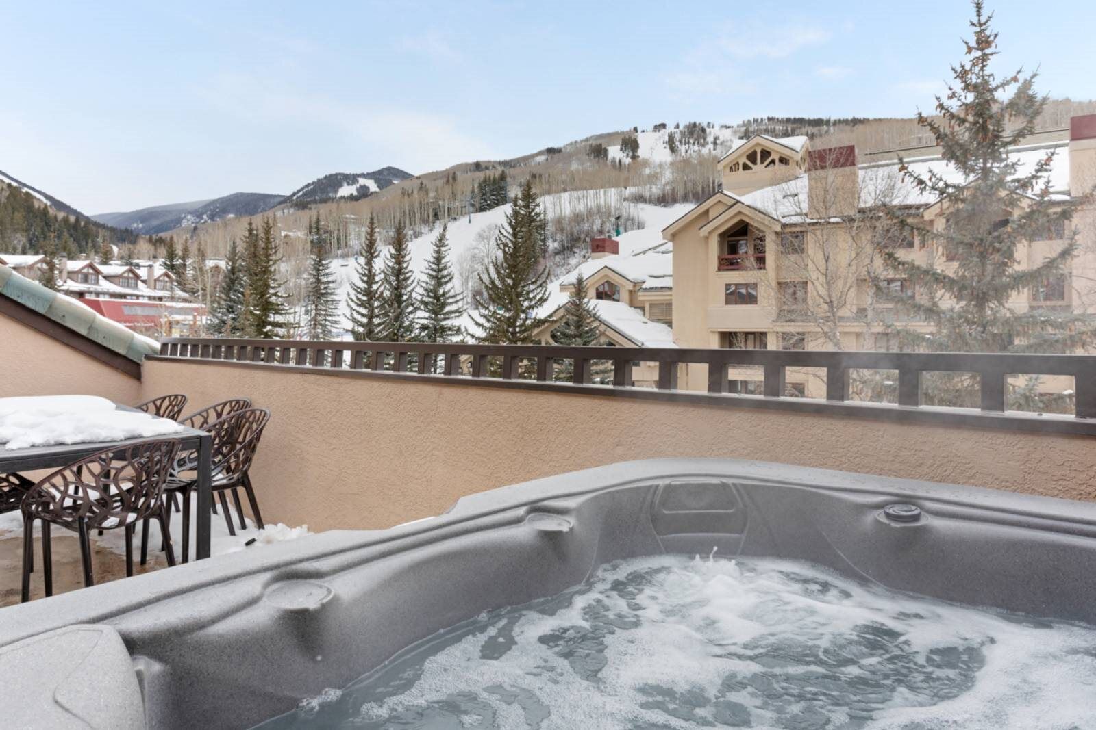 Un jacuzzi en un balcón con vista a una montaña y edificios.