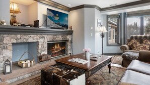 A cozy living room with a stone fireplace, a large window, and a comfortable seating area.
