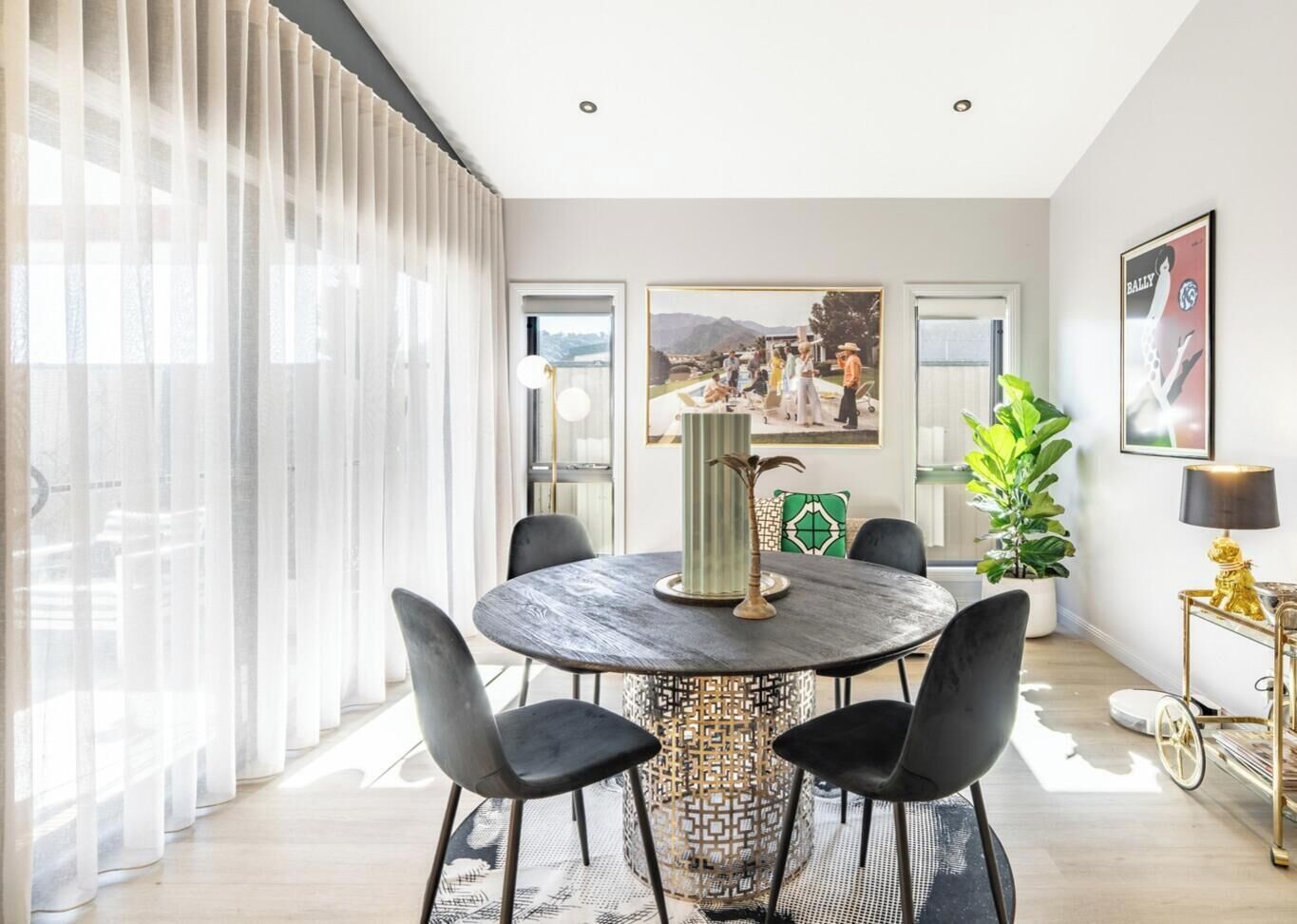 A dining area with a round table, black chairs, a decorative vase, and a painting on the wall.