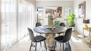 Un comedor con una mesa redonda, sillas negras, un jarrón decorativo y un cuadro en la pared.
