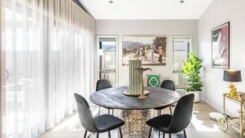 A dining area with a round table, black chairs, a decorative vase, and a painting on the wall.