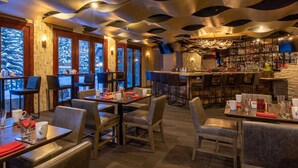 A restaurant with a modern interior, featuring a bar area with a stone wall and a variety of seating options including tables and chairs. - Gorgeous 4 Bedroom Ski In/out Condo in Beaver Creek Village (Avon)