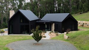 A modern black building with a symmetrical design, large windows, and a stone pathway leading to the entrance. - Balangara, Exeter, Southern Highlands (Exeter)