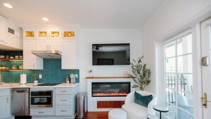 A modern kitchen with white cabinetry, a built-in oven, and a fireplace.
