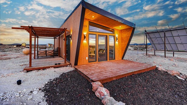 Eine moderne Holzhütte mit Satteldach, einer Terrasse und einem Eingang mit Glasdoor.