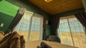 Ein Zimmer mit Oberlicht, großen Fenstern, einem Bett und Blick auf die Landschaft.