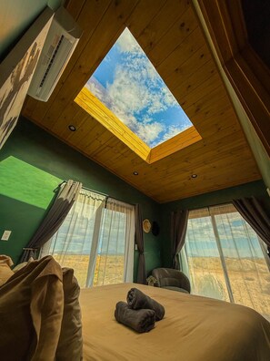 Una habitación con tragaluces, ventanas amplias, una cama y vistas al paisaje.