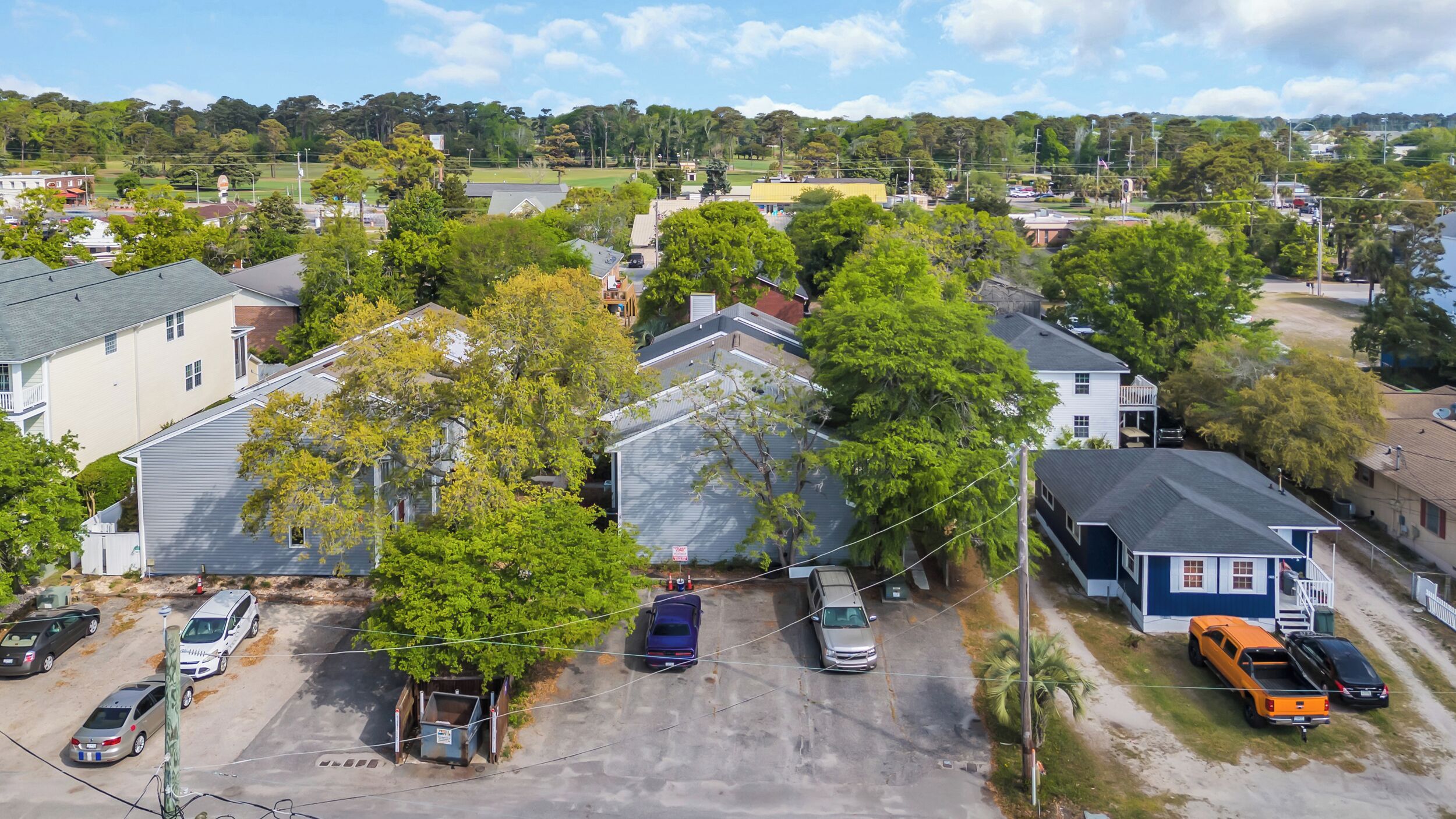 A residential area with houses, a parking lot, and a clear sky.
