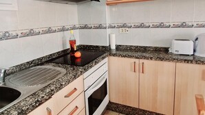 A kitchen with granite countertops, wooden cabinets, a stainless steel range hood, a toaster, and a kettle. - Los Angeles 1 bedroom pool view 520 (ARONA)