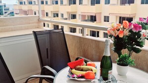 A balcony with a table set for two, featuring a bottle of champagne, a fruit bowl, and a vase of flowers. - Los Angeles 1 bedroom pool view 520 (ARONA)