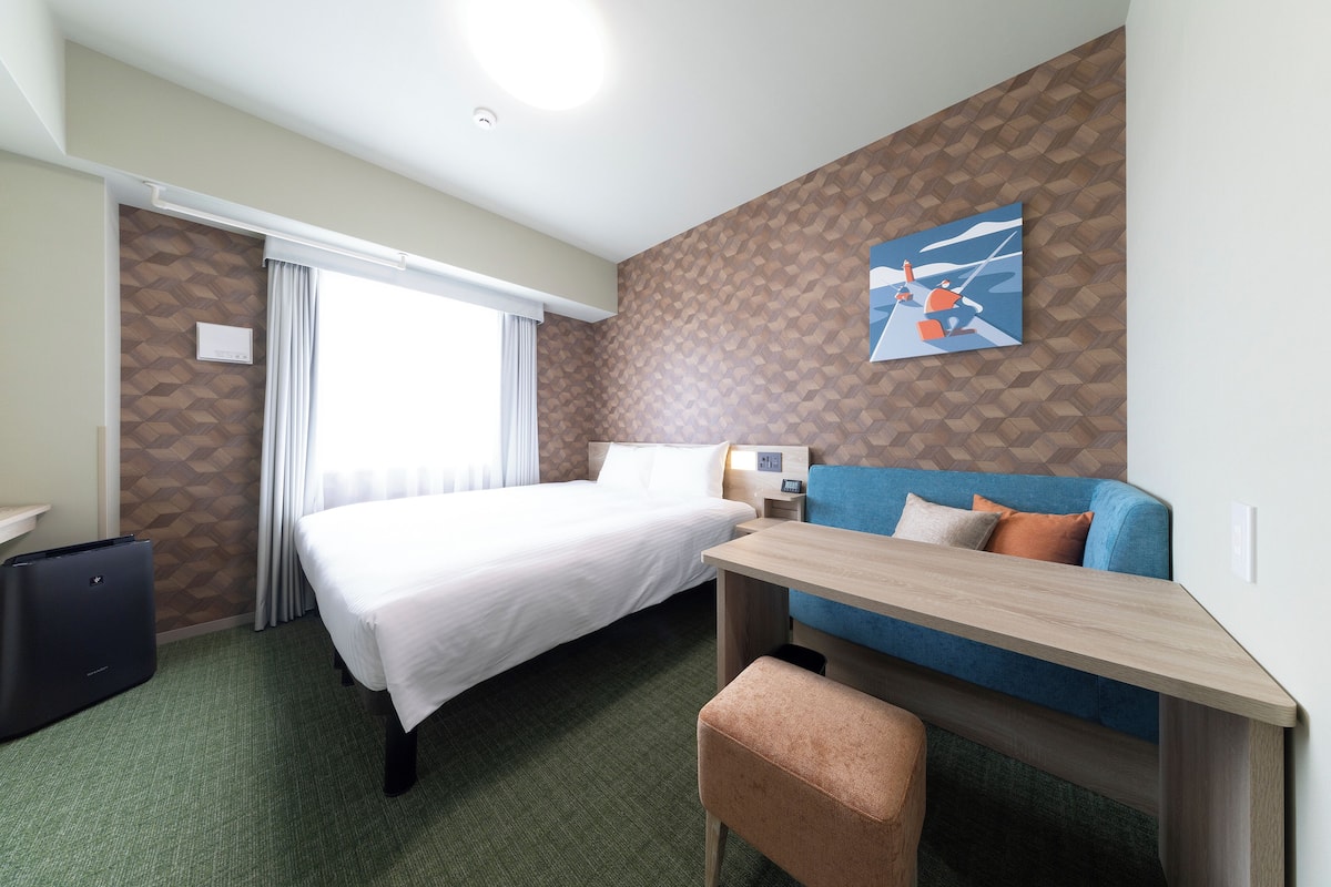 Ein Hotelzimmer mit einem Bett, einem Schreibtisch, einem Sessel und einer blauen Couch.
