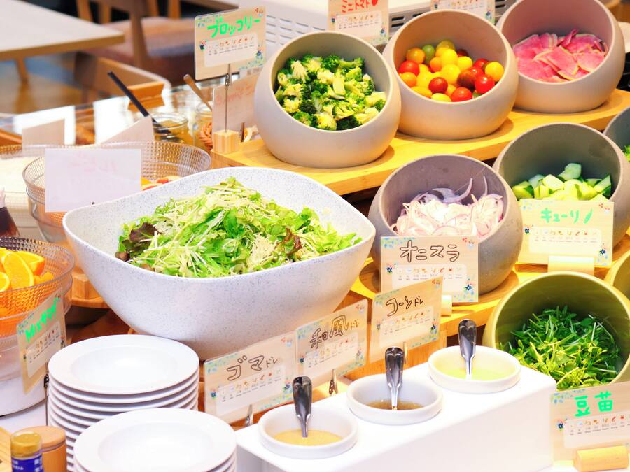 Un buffet con diverse opzioni tra cui insalate, verdure e frutta.