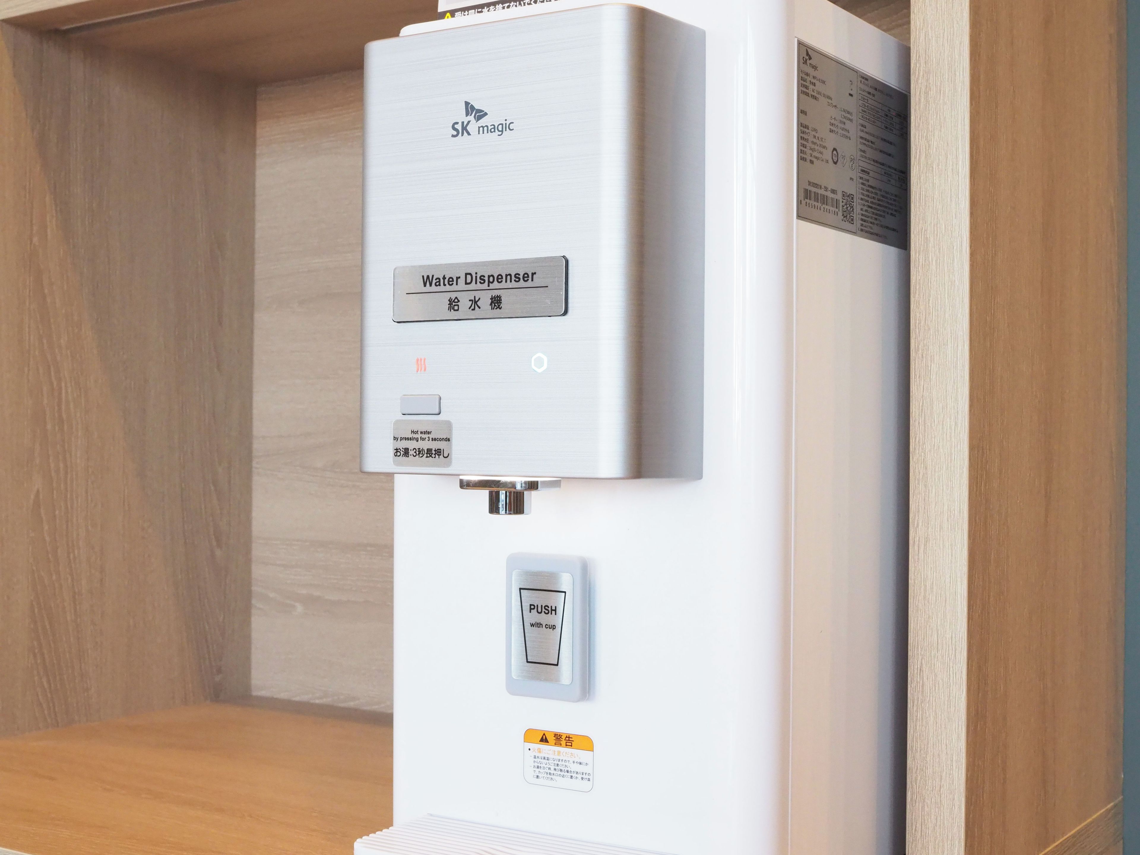 A water dispenser with a push button and a warning label.