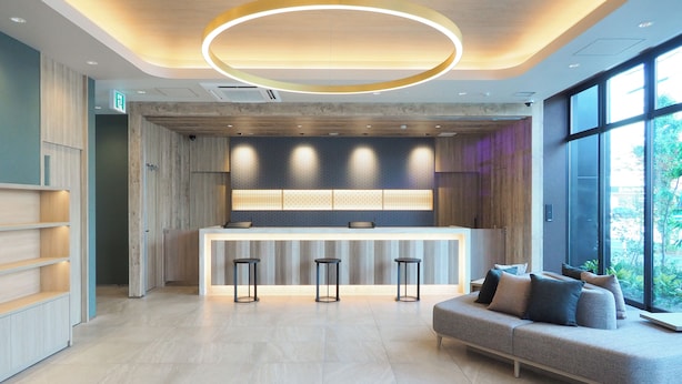 A modern reception area with a central desk, bar stools, and a sofa.