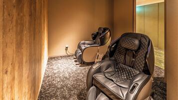 A massage chair in a room with a wooden accent wall and carpeted floor.
