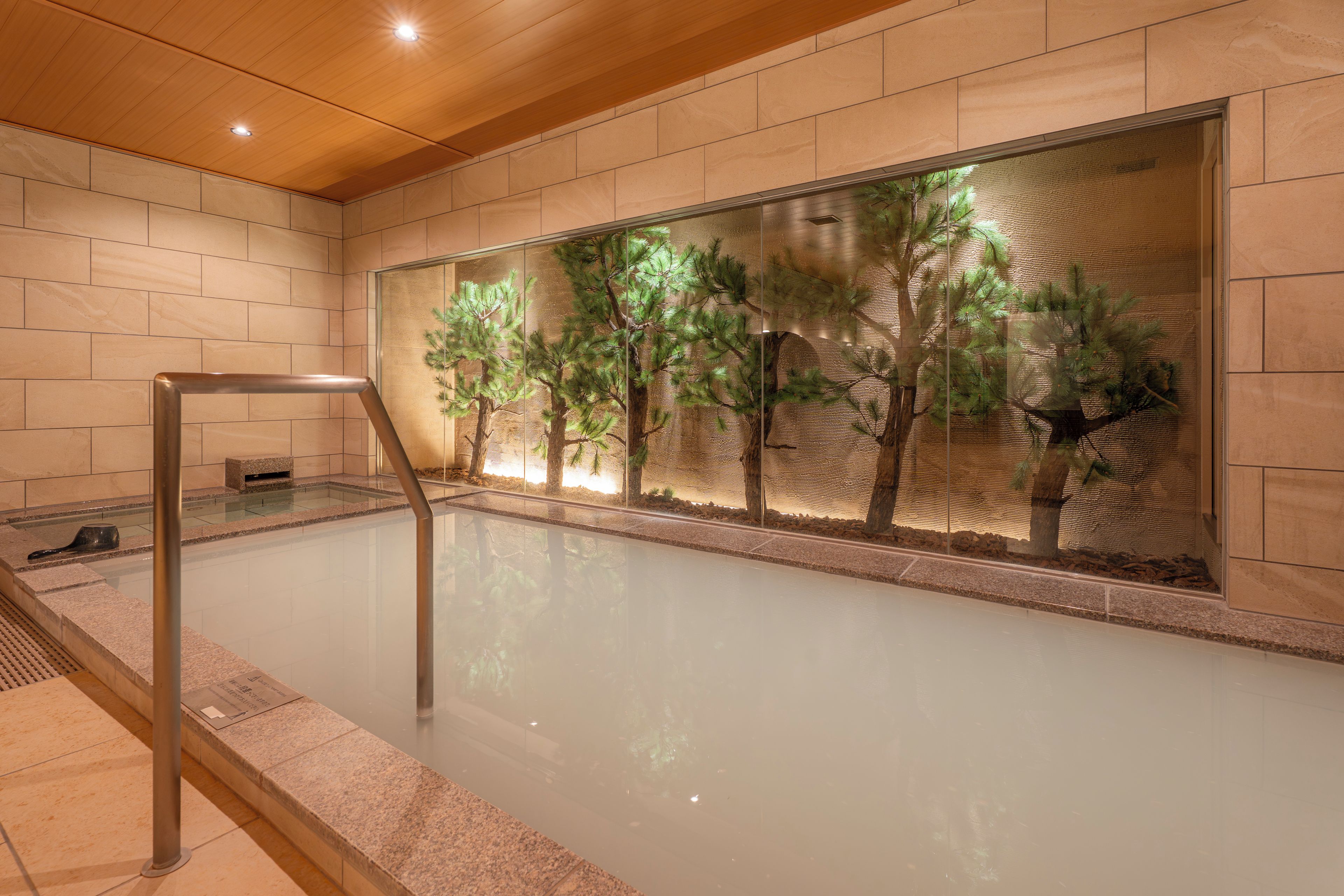 A spa area with a glass wall, a wooden ceiling, and a metal railing.