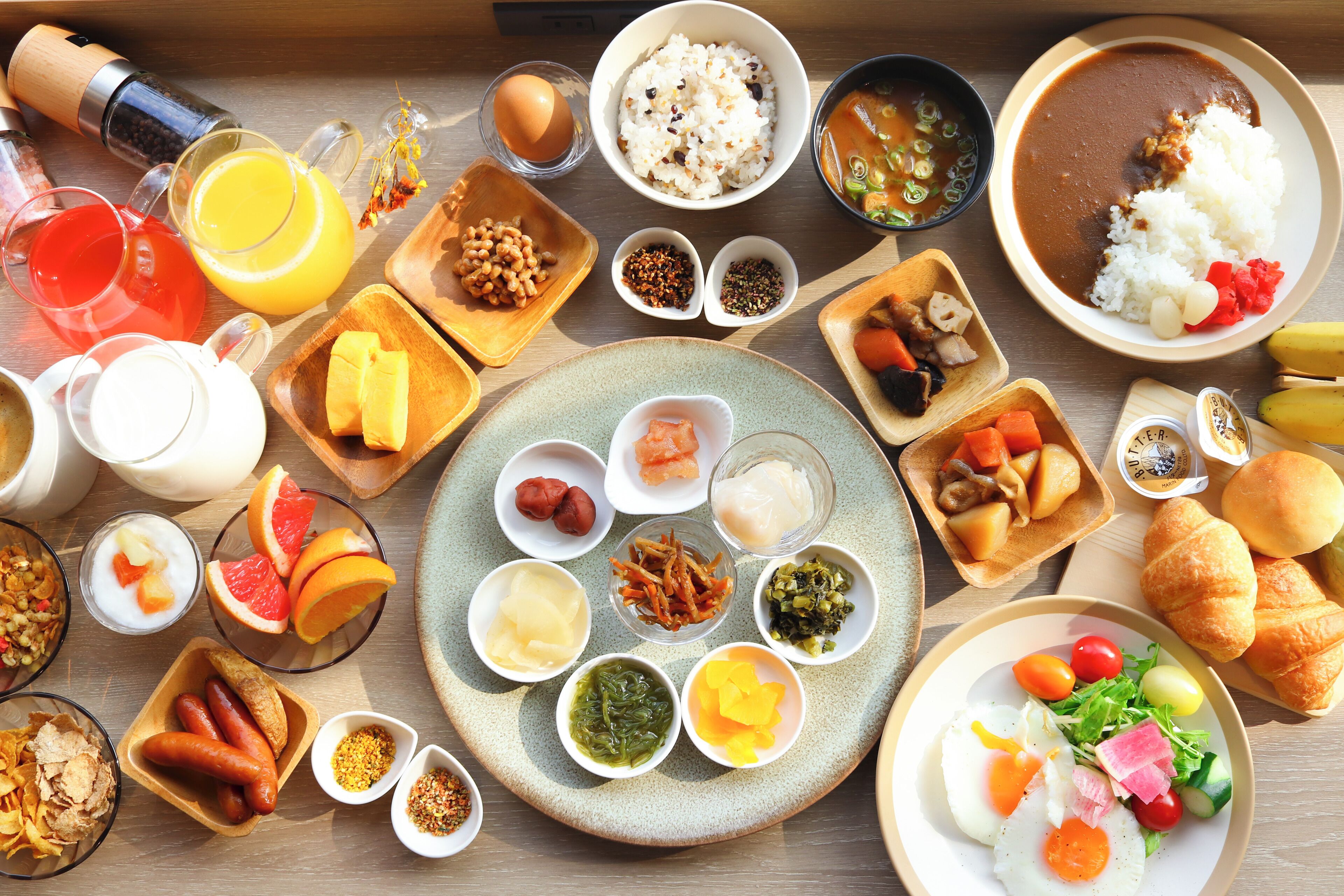 Variedad de alimentos para el desayuno, como huevos, salchichas y verduras, sobre una mesa de madera.