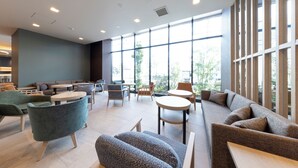 A modern interior with seating areas, tables, and large windows providing natural light.