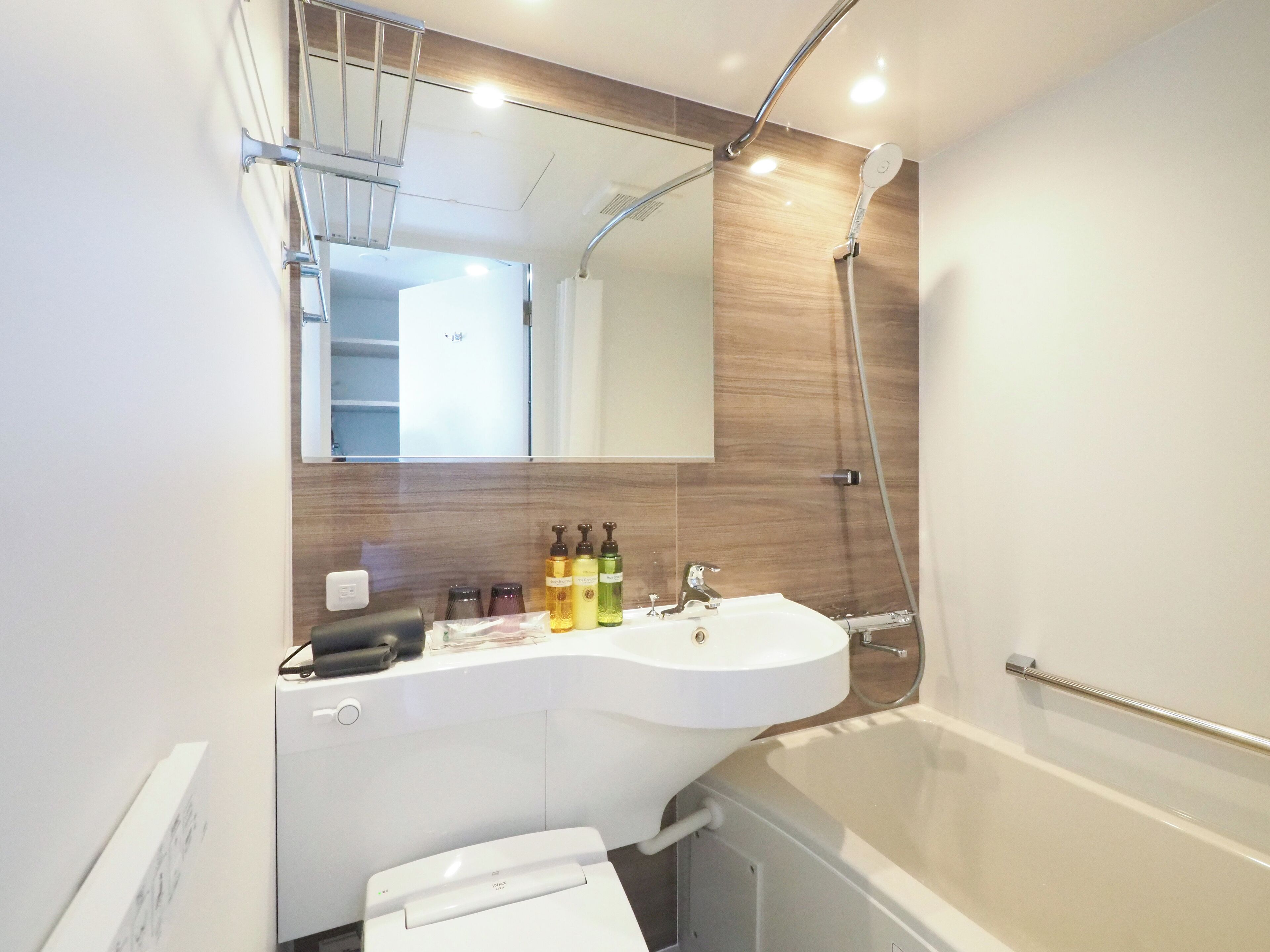 Ein modernes Badezimmer mit einem weißen Waschbecken, einem Spiegel darüber und einer Duschbrause.