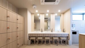 A modern bathroom with a large mirror, multiple sinks, and wooden lockers.