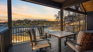 A wooden deck with a table and chairs overlooking a body of water and a residential area. - Accessible Lakeside Luxury at the 45mm w/ Private Dock, Sunset Views & More (Climax Springs)