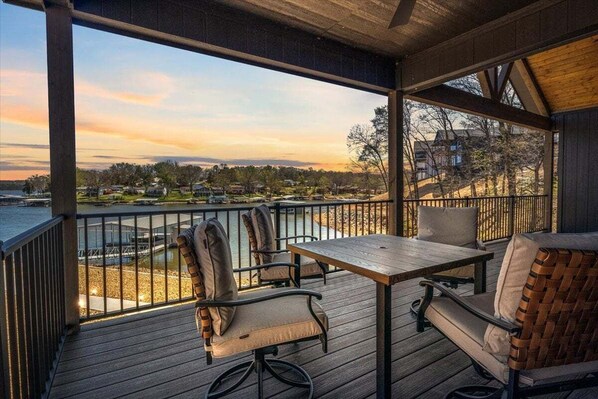 A wooden deck with a table and chairs overlooking a body of water and a residential area.