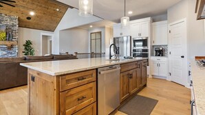 A modern kitchen with wooden cabinetry, a central island with a dishwasher, and pendant lighting. - Accessible Lakeside Luxury at the 45mm w/ Private Dock, Sunset Views & More (Climax Springs)