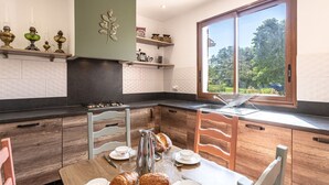 Una cocina moderna con estufa a gas, armarios de madera y una mesa de comedor lista para el desayuno.